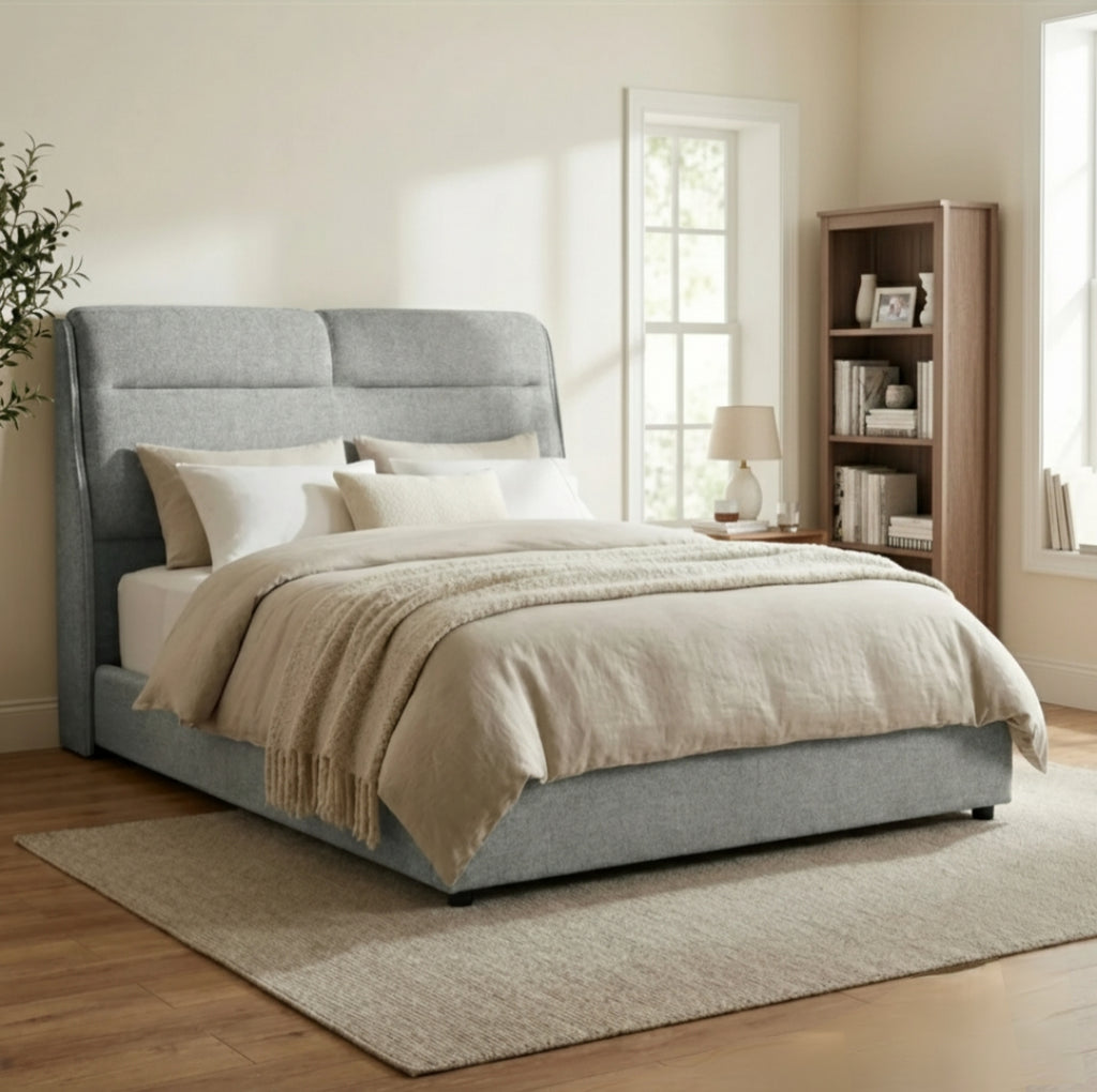 Gray upholstered bed with beige bedding in a bedroom setting.